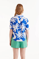 Woman wearing large print blouse in blue and white paired with green shorts 