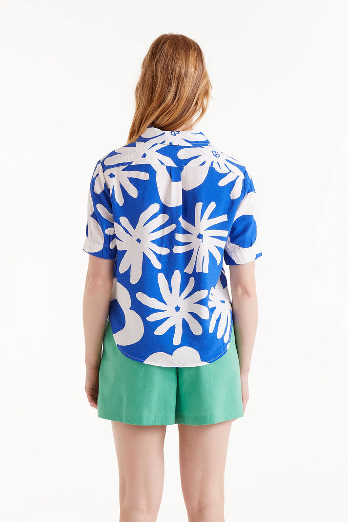 Woman wearing large print blouse in blue and white paired with green shorts 