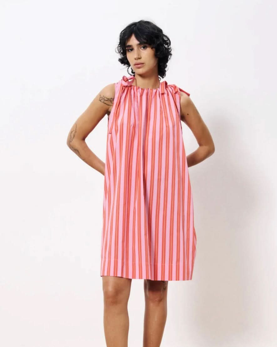 Woman wearing a pink and white striped dress against a white background
