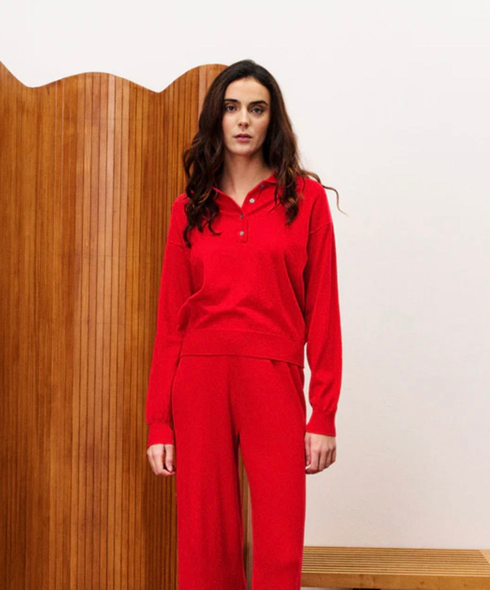 Person wearing a red outfit standing against a wooden panel background