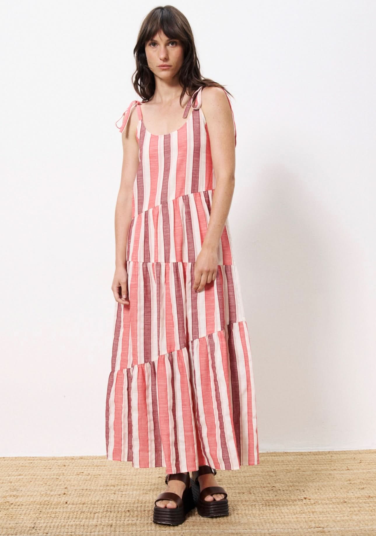 Woman wearing red, burgundy and white griped liner dress straps tied at shoulder 