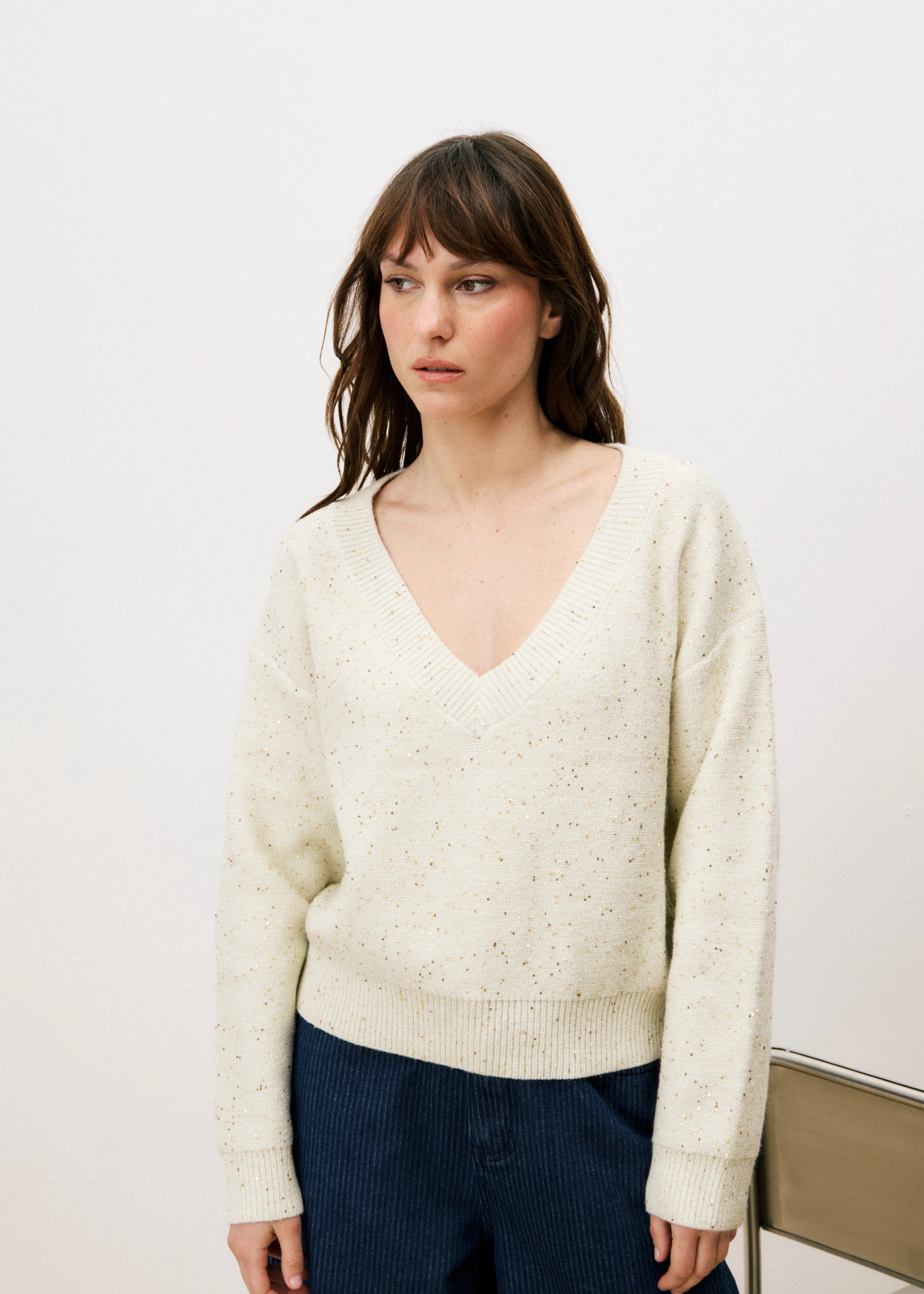 Woman wearing a cream sweater with small dots and v shape neck