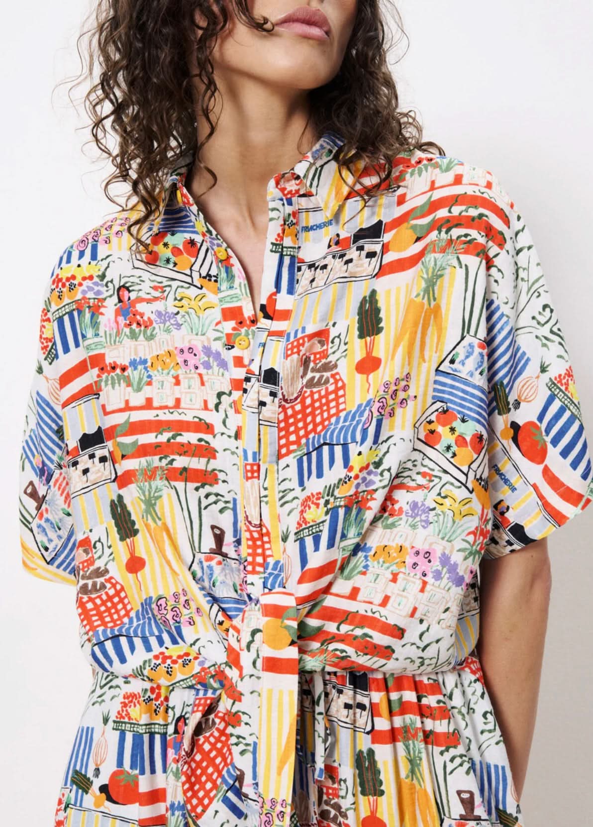 Woman wearing a colorful patterned dress against a plain background