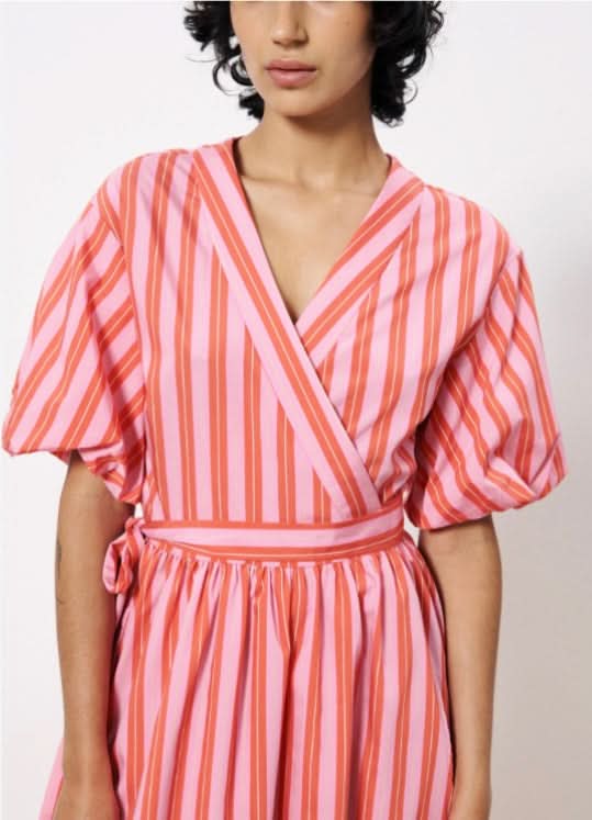 Woman wearing a red and pink striped wrap maxi dress with short puff sleeves and side pockets, wrap tie around waist