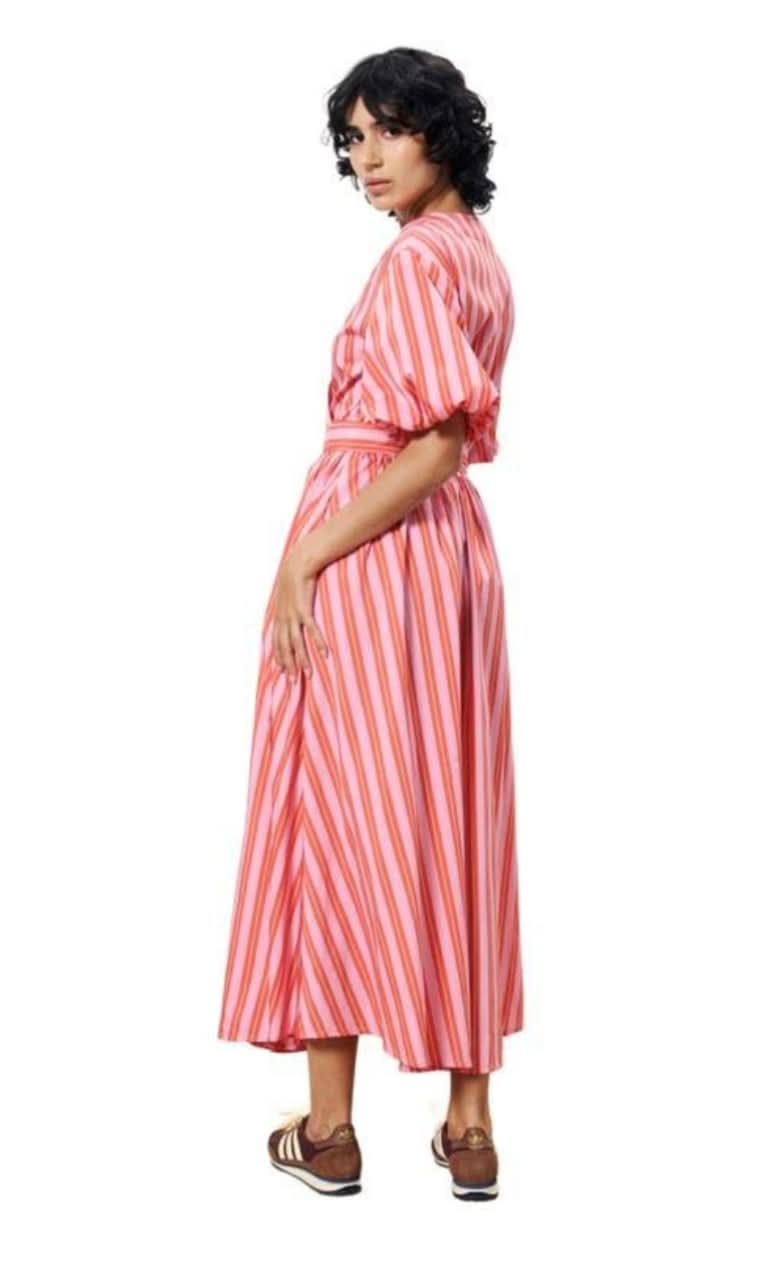 Woman wearing a red and pink striped wrap maxi dress with short puff sleeves and side pockets, wrap tie around waist