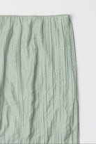 sea foam, Sage green textured skirt laid against a white surface 
