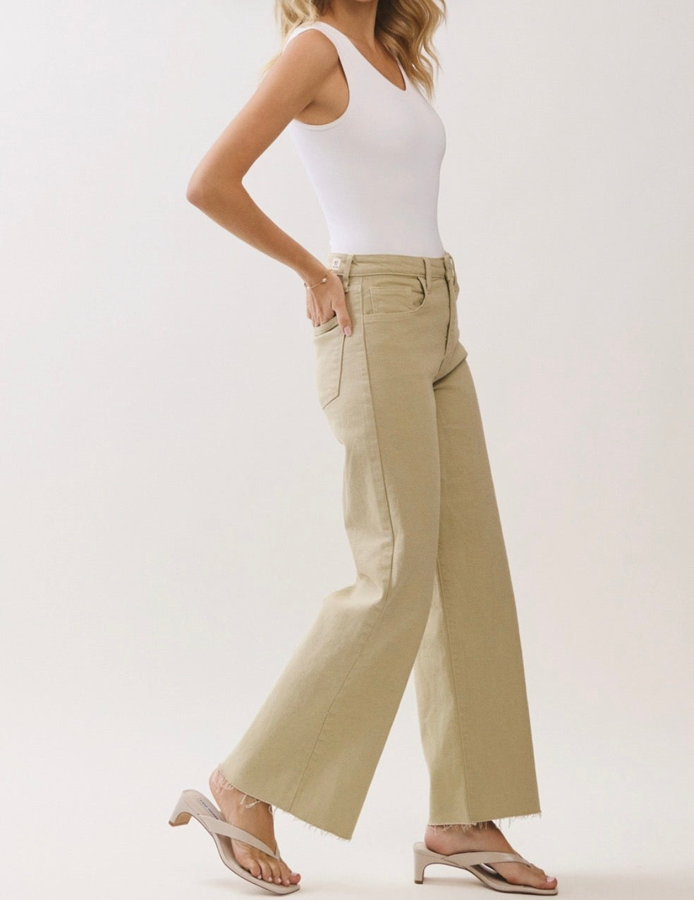 Person wearing beige wide-leg pants and a white top on a plain background