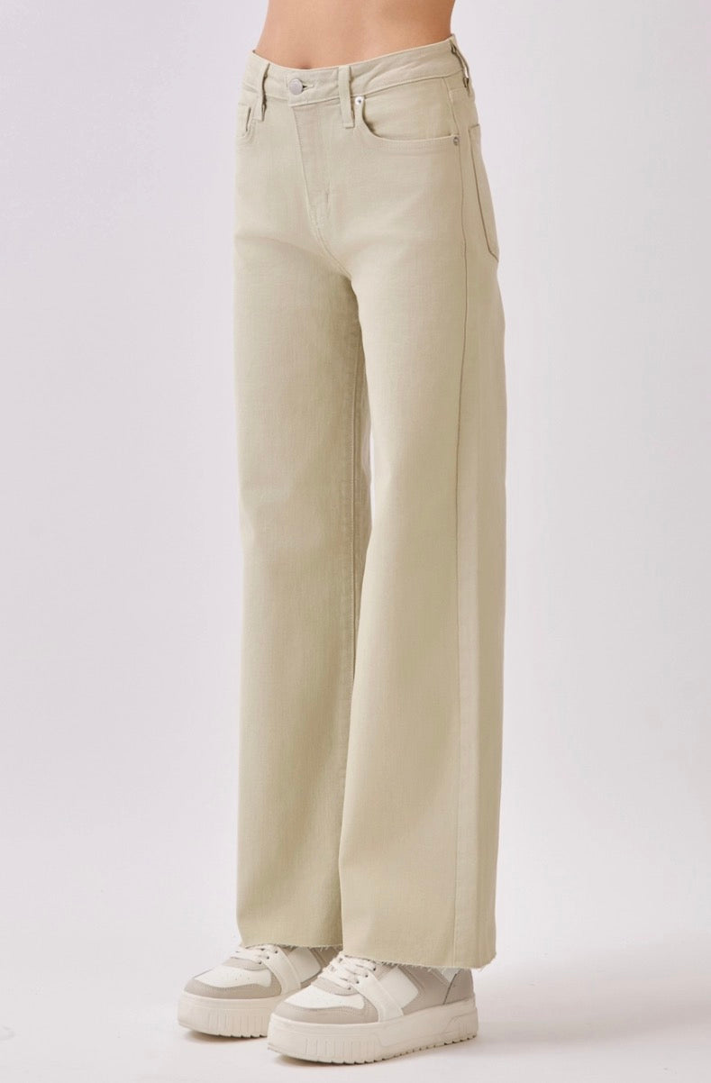 Beige wide-leg jeans worn with white sneakers on a light gray background