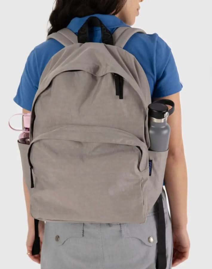 Person wearing Taupe nylon backpack with front pocket zip closure water bottle pockets on each side 