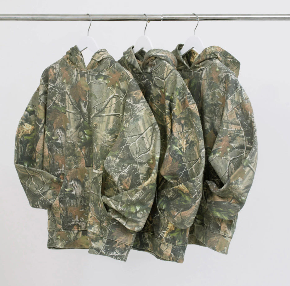 Three Vintage camo real tree cotton pullover hoodie sweatshirts hanging on hangers 