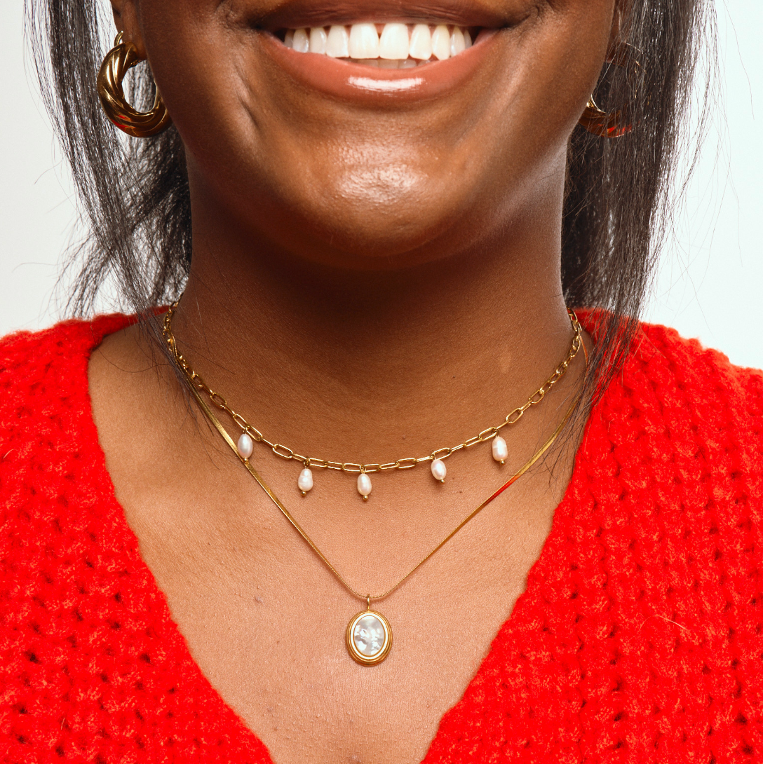 Woman wearing Gold pearl shell necklace with thin herringbone chain