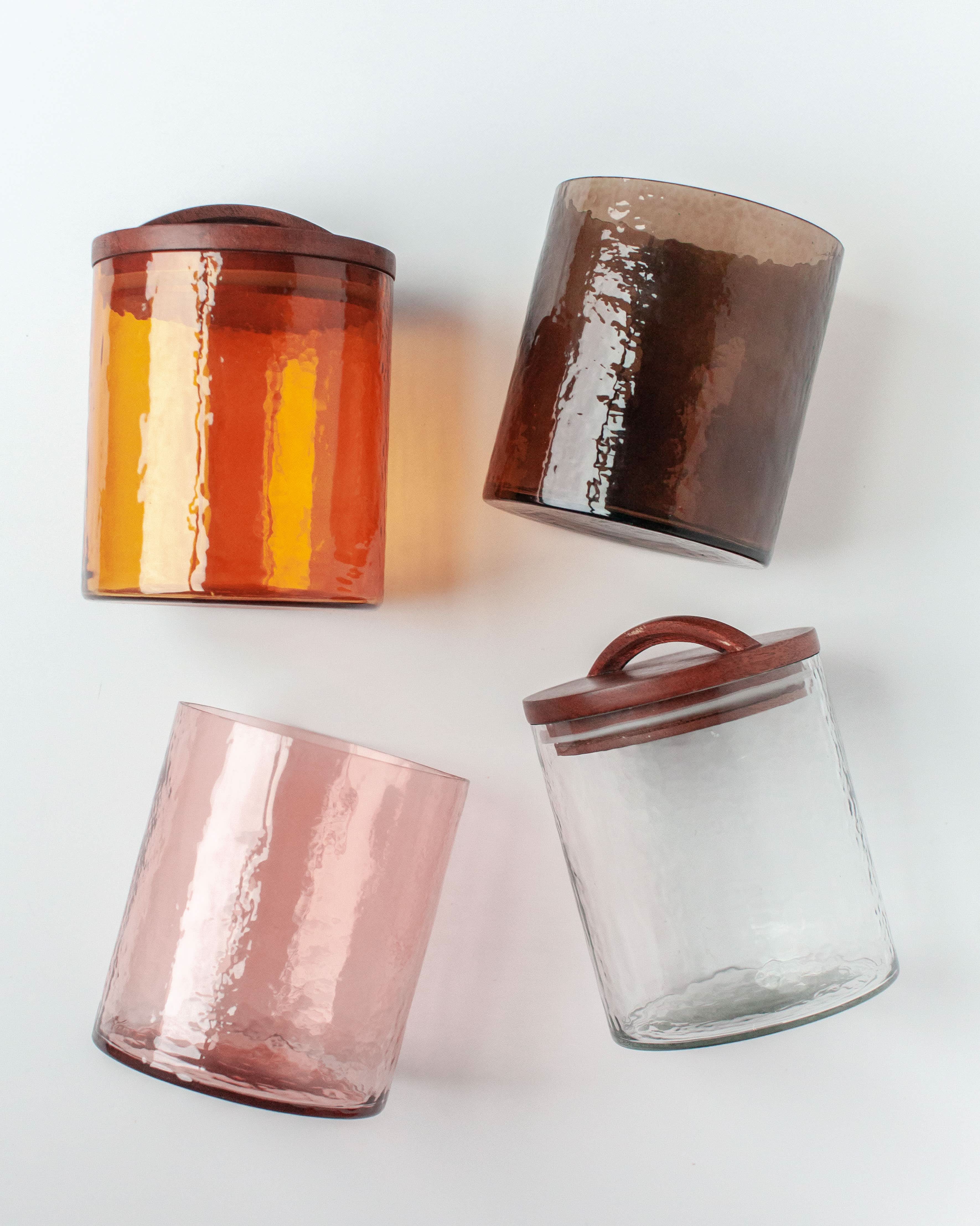 Four glass jars with metallic lids on a white background