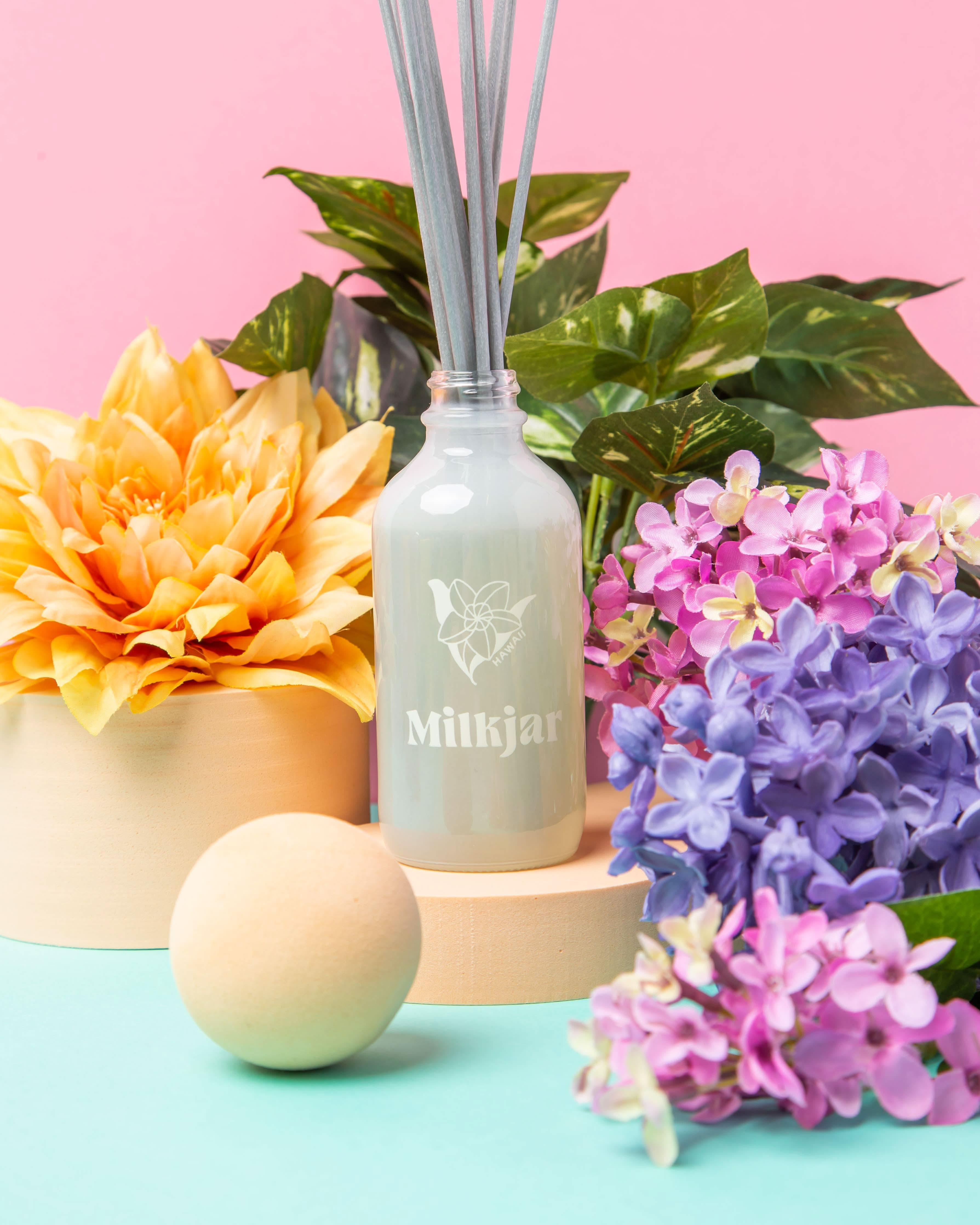 Milkjar Hawaii Lilac & Plumeria Reed bottle with flowers and a bath bomb.