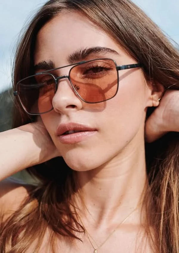 Model wearing aviator style sunglasses with brown