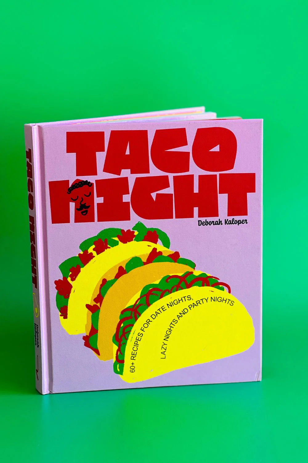 Pink “Taco Night” recipe book slightly open on green background 