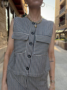 Woman standing outside wearing Striped denim and cream vintage vest, full button up, with big pockets in front 