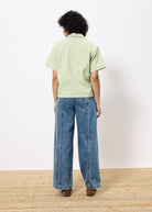 Woman facing backward wearing yellow green and white gingham cropped blouse paired with wide leg jeans 