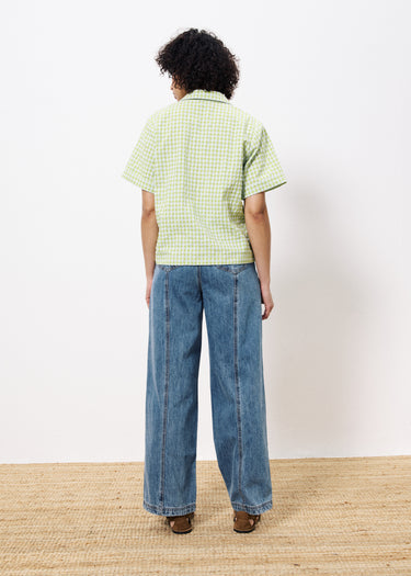 Woman facing backward wearing yellow green and white gingham cropped blouse paired with wide leg jeans 