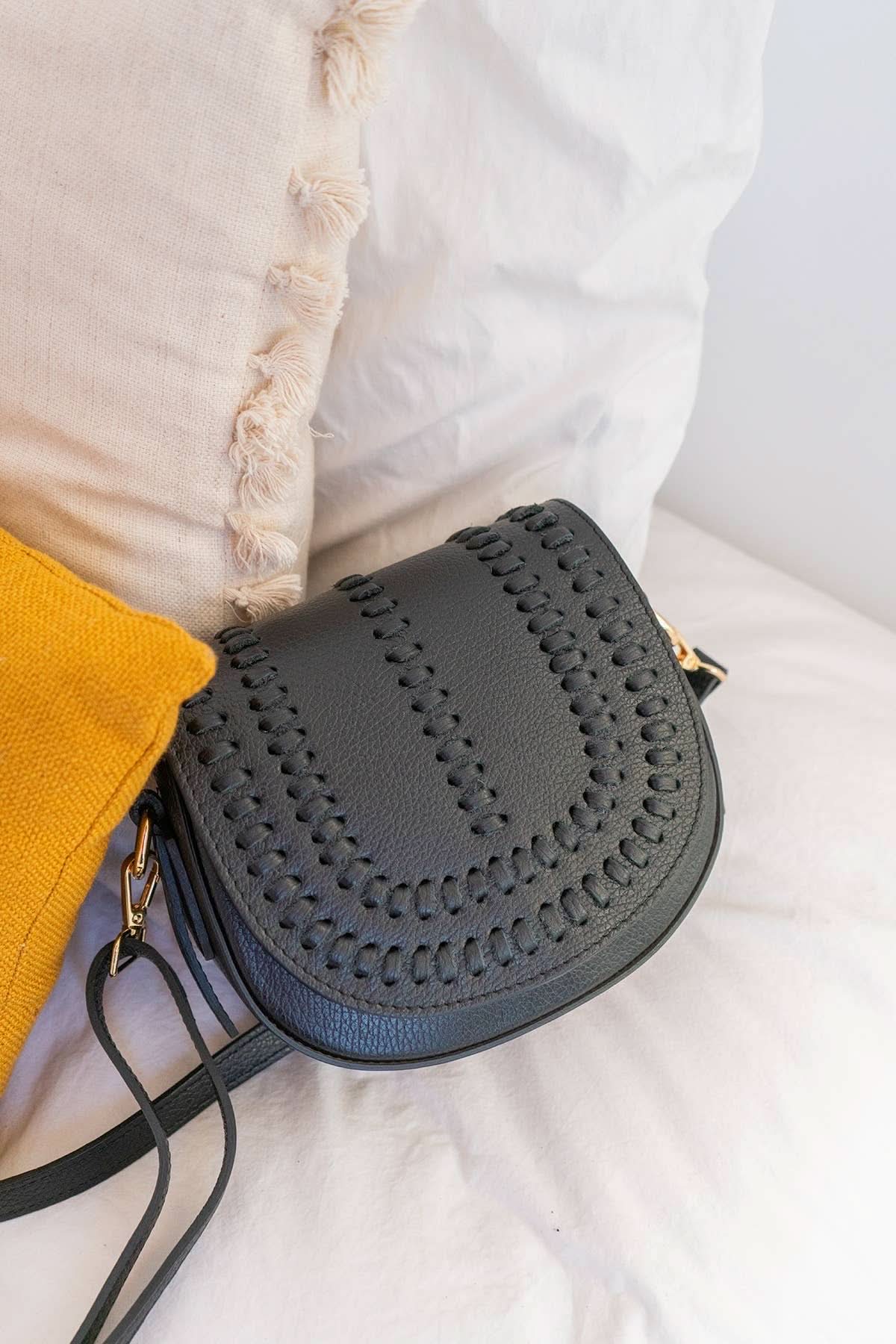 Black colored leather crossbody bag with magnetic front clap and leather woven geometric design and gold Metal details 