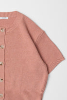 Close up detail of a salmon pink, short sleeved, sweater cardigan 