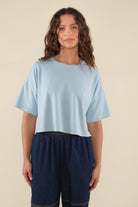 Woman wearing light sky blue , short sleeve, jersey, cropped t-shirt and blue jeans 