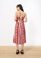Woman wearing colorful maxi dress with red, pink, brown , purple, and blue shapes and striped throughout and cross tie back 