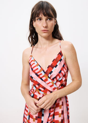 Woman wearing colorful maxi dress with red, pink, brown , purple, and blue shapes and striped throughout 
