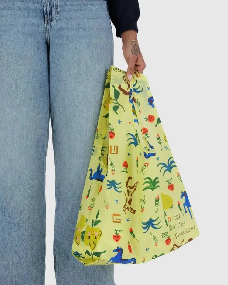 Woman carrying Pear green baby baggu reuseable grocery with painted prairie designs throughout the bag