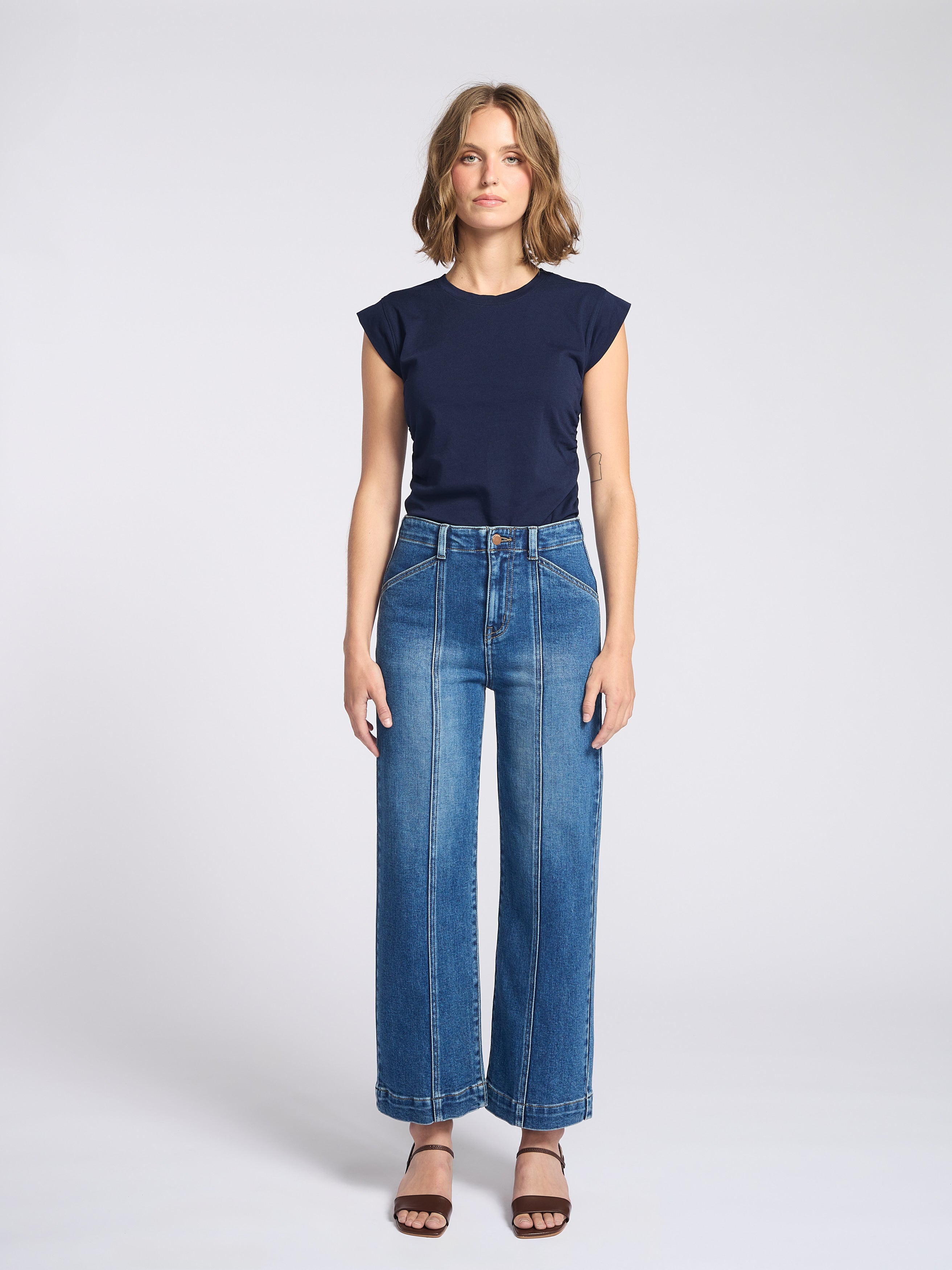Woman wearing wide legs dark jeans with seam down the front of each pant leg with navy blue shirt
