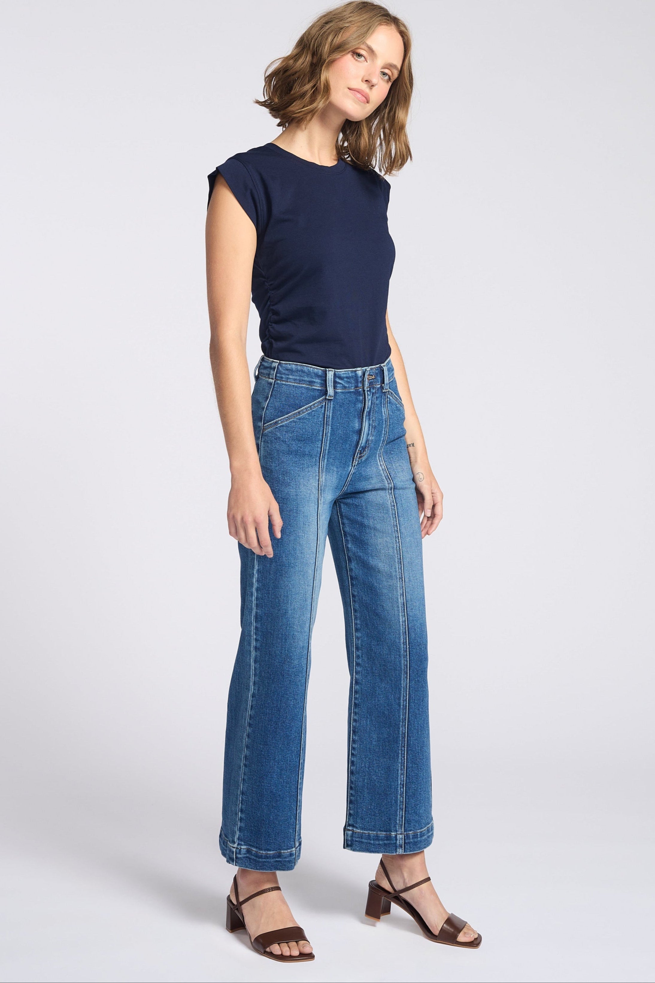 Woman wearing wide legs dark jeans with seam down the front of each pant leg with navy blue shirt