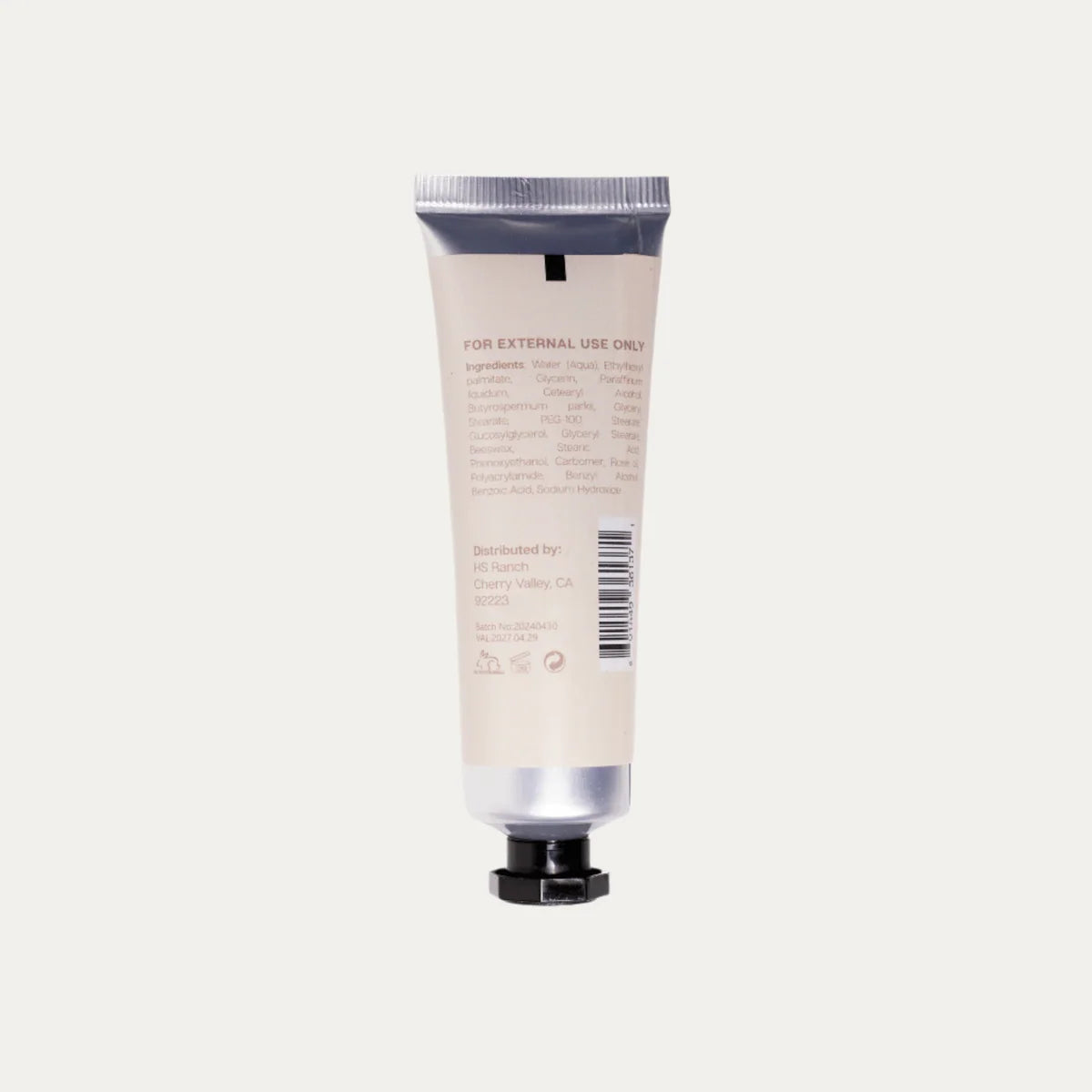 Hand cream tube with silver cap and black base on a light gray background