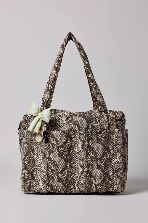Snakeskin patterned handbag with a bow on a light gray background