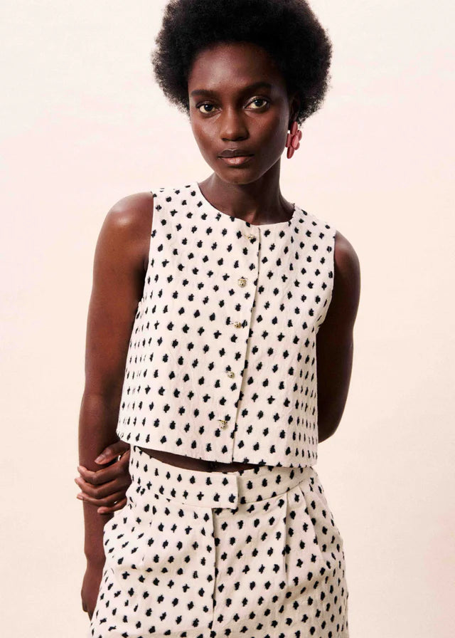 Woman wearing a polka dot outfit against a plain background