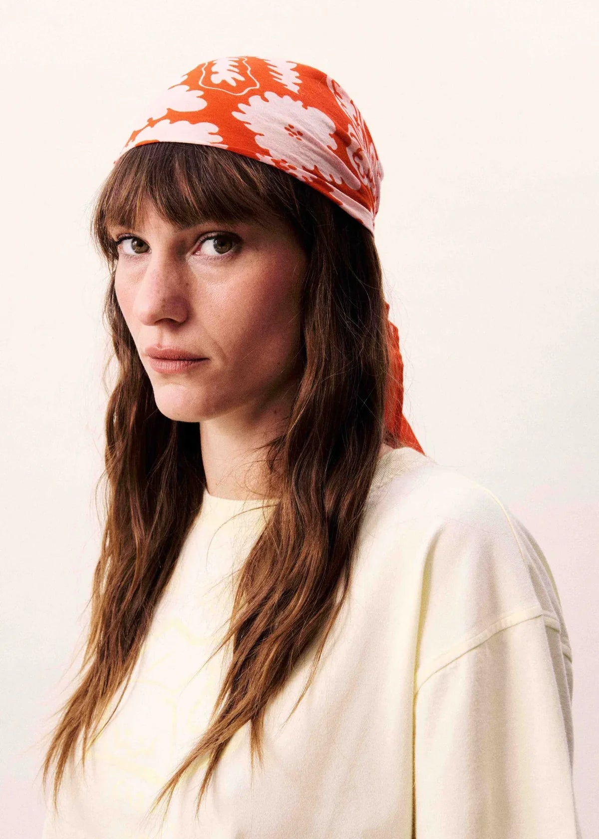 Woman wearing a red floral headscarf on a white background