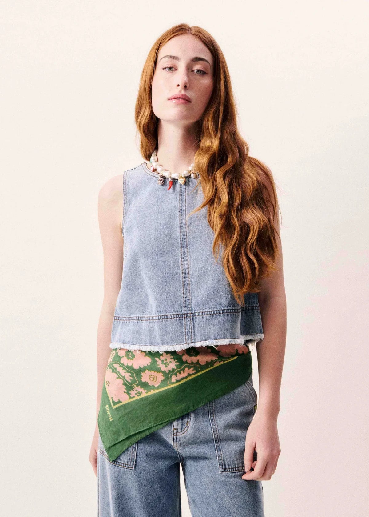 Woman wearing a denim top and floral scarf on a light pink background
