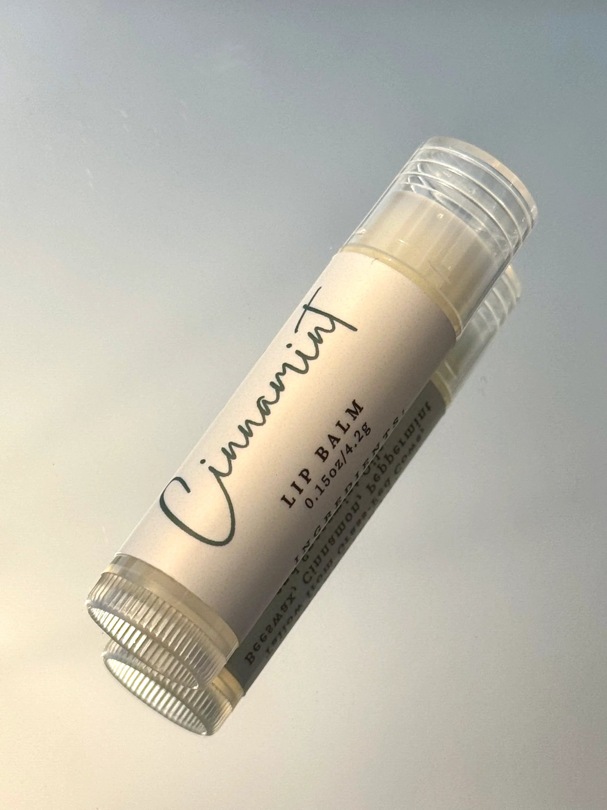 Lip balm stick with 'Cinnamint' branding on a gradient background