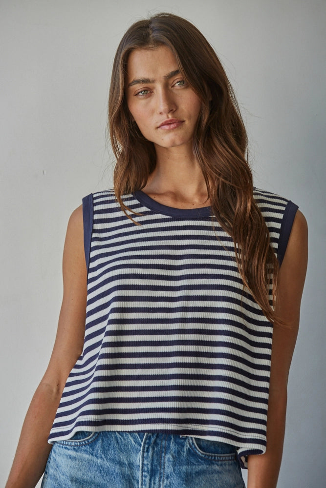 Woman wearing a navy and white striped sleeveless top against a plain background