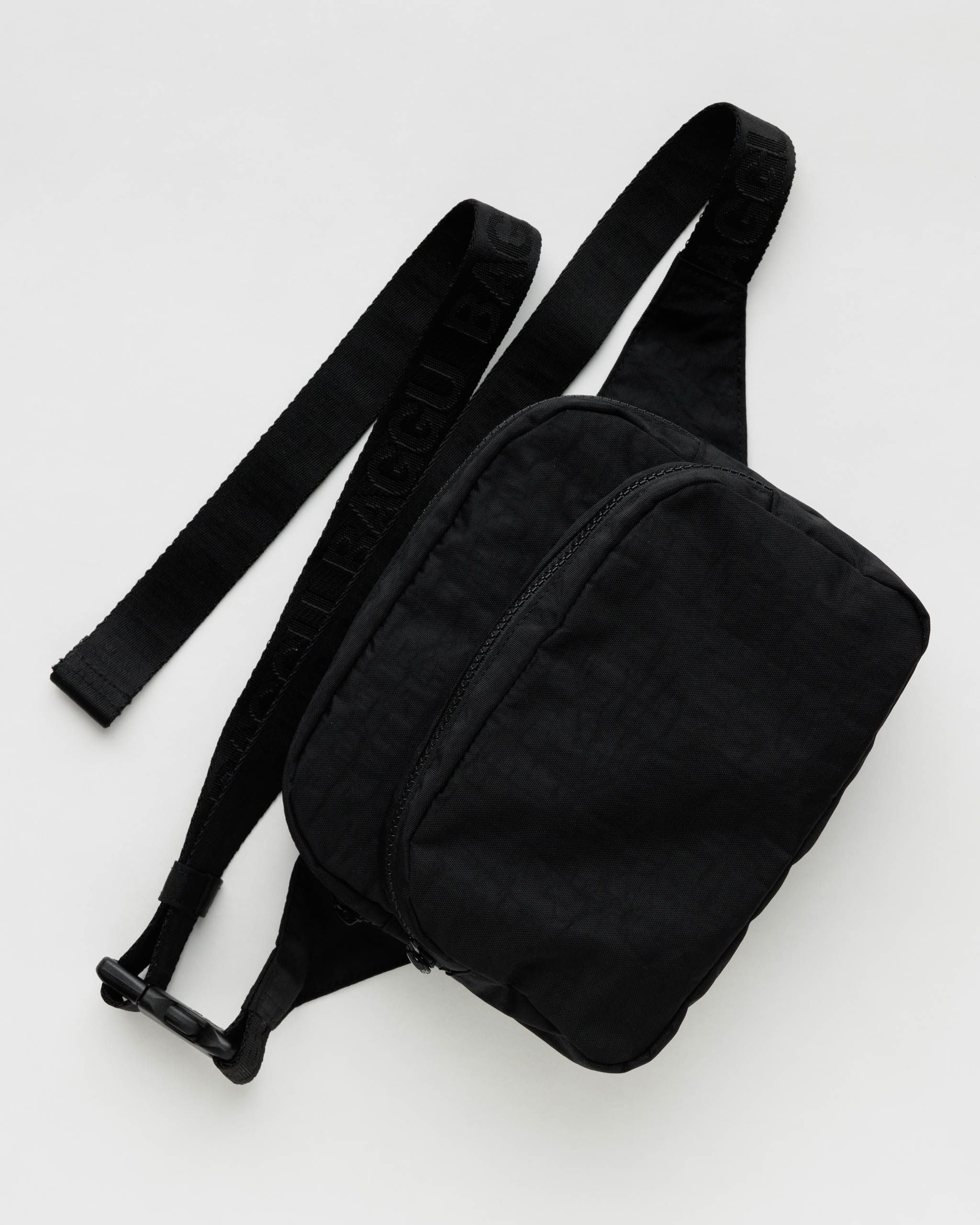 Black waist bag with a strap on a light gray background