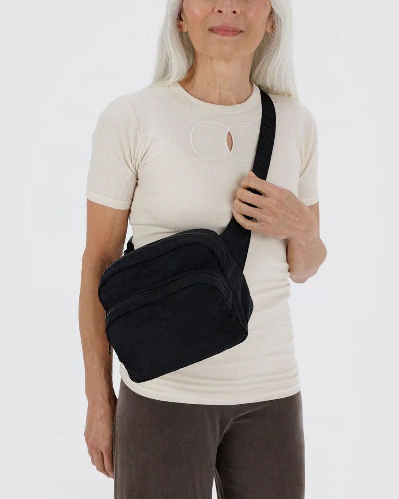 Person wearing a black crossbody bag on a white background