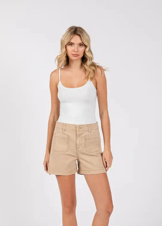 Woman wearing a white tank top and beige shorts on a white background