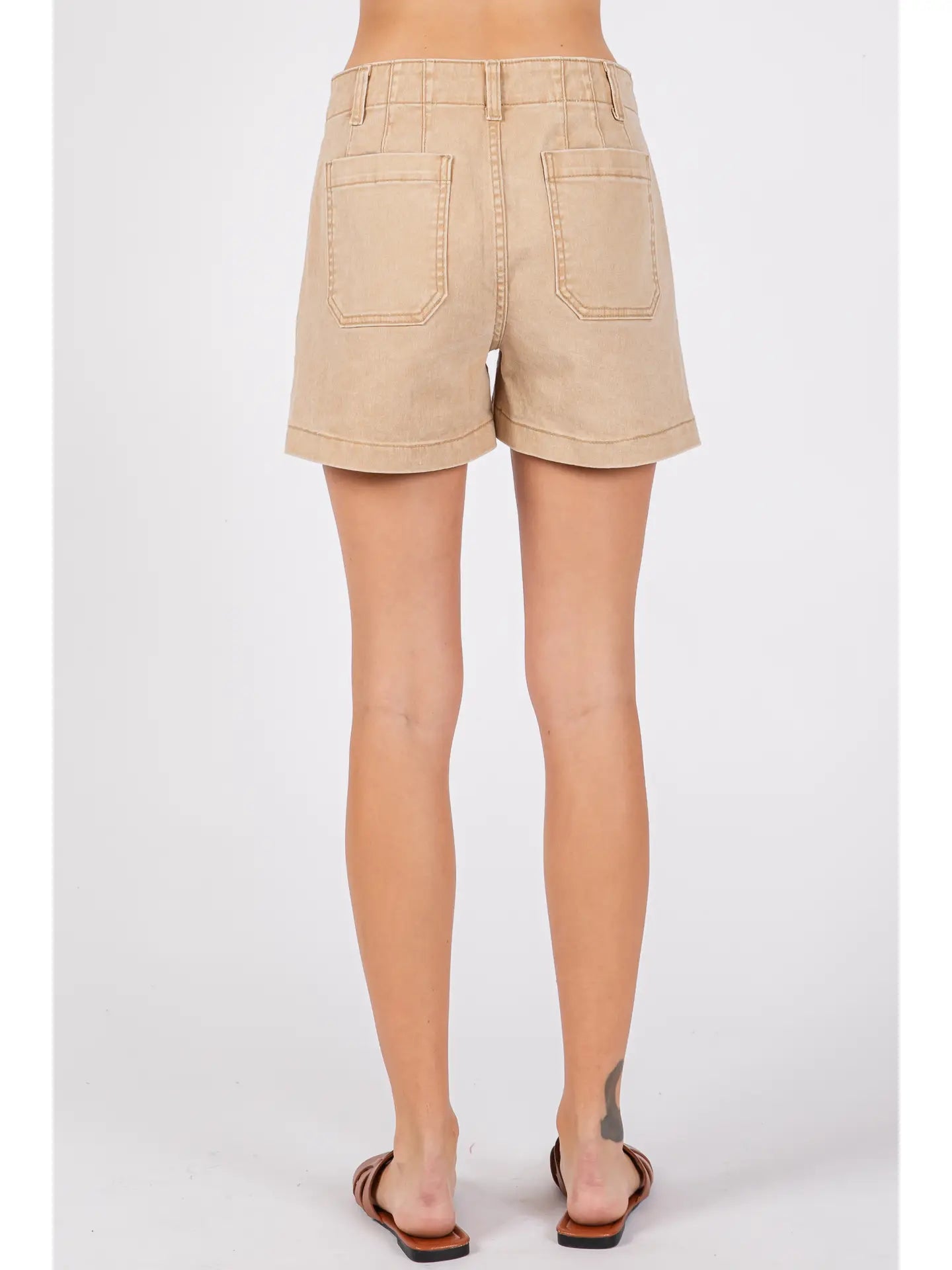 Beige shorts worn by a person on a white background