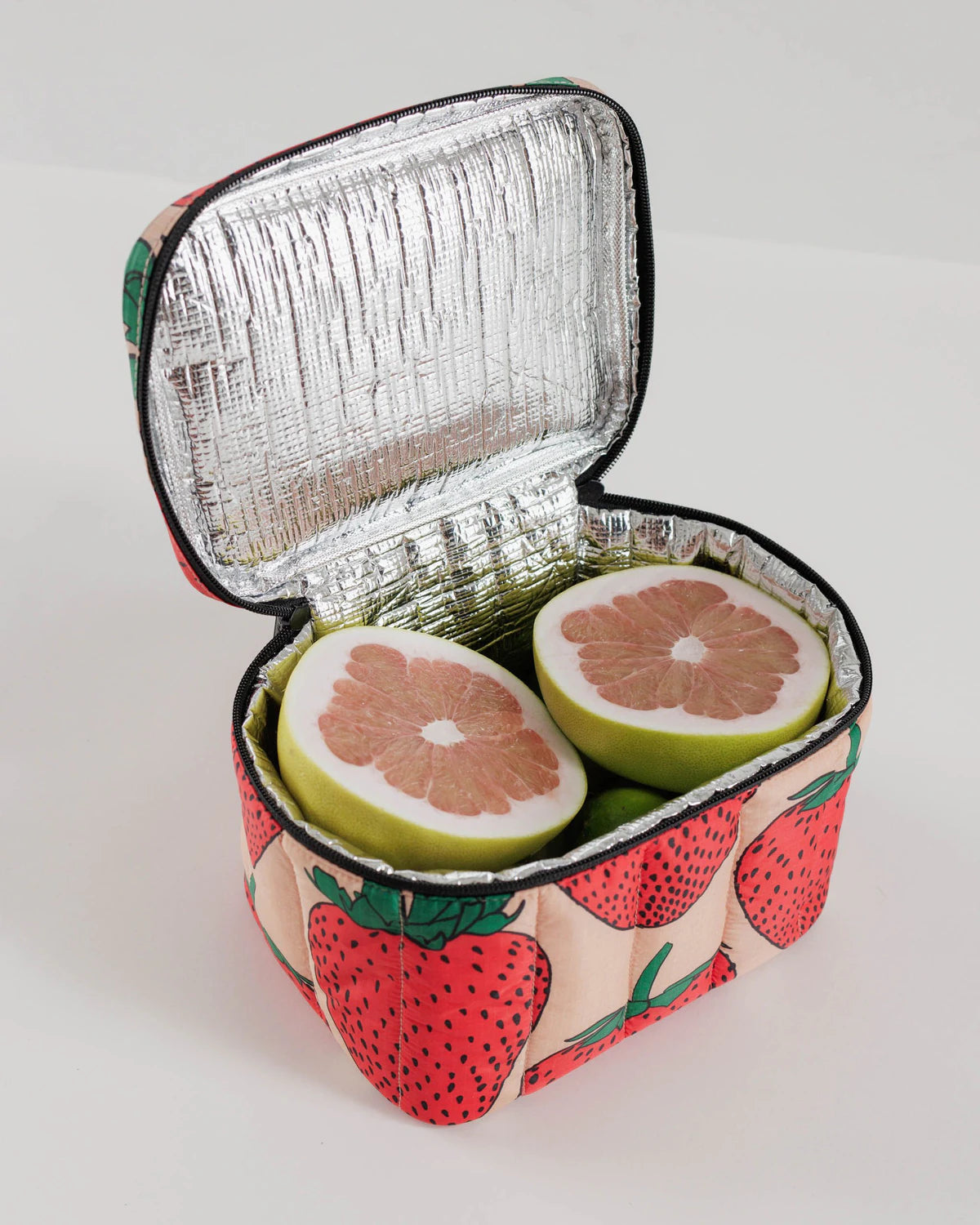 Insulated lunch bag with fruit design containing sliced grapefruits on a white background