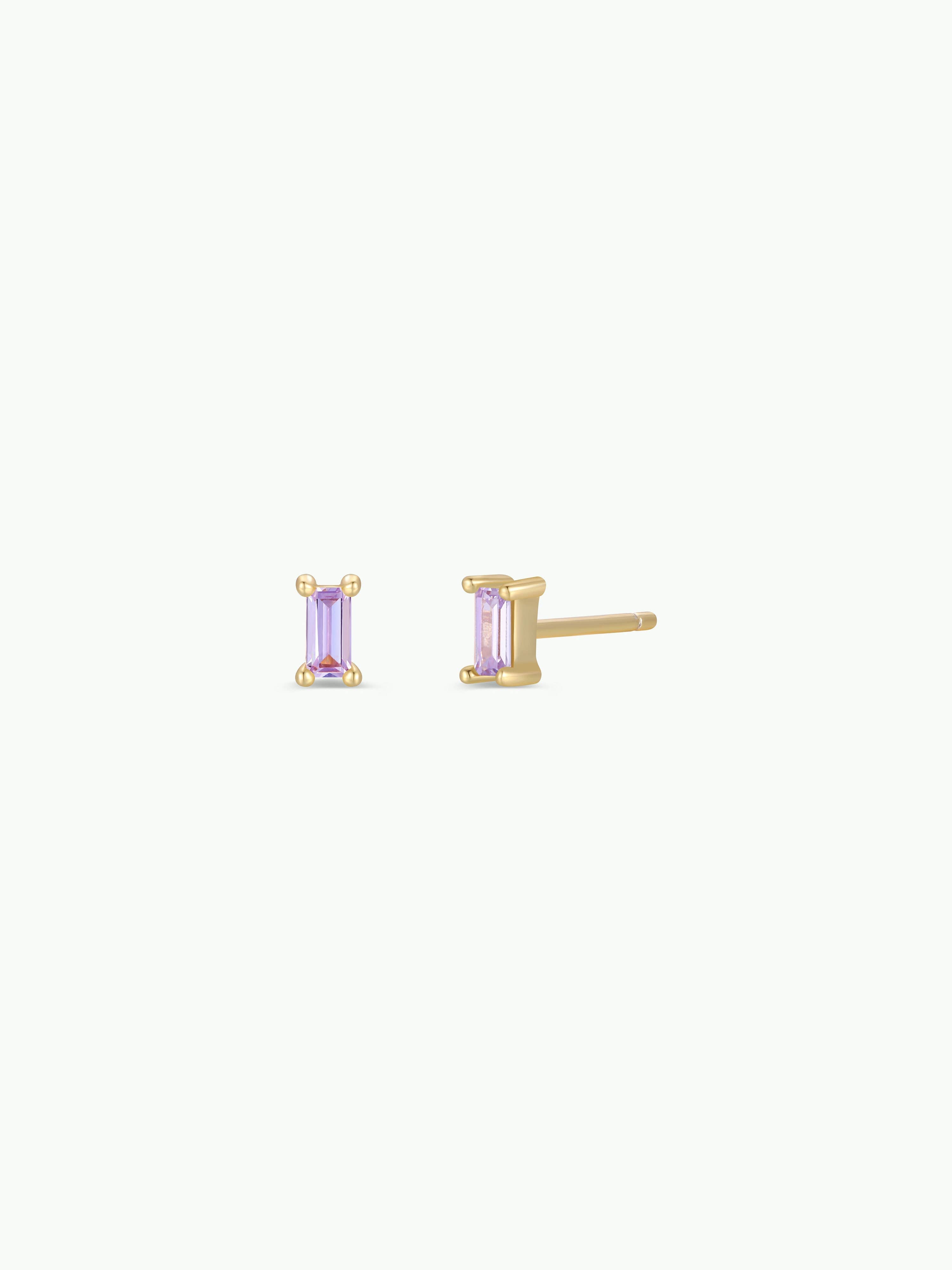 Gold earrings with purple gemstones on a white background