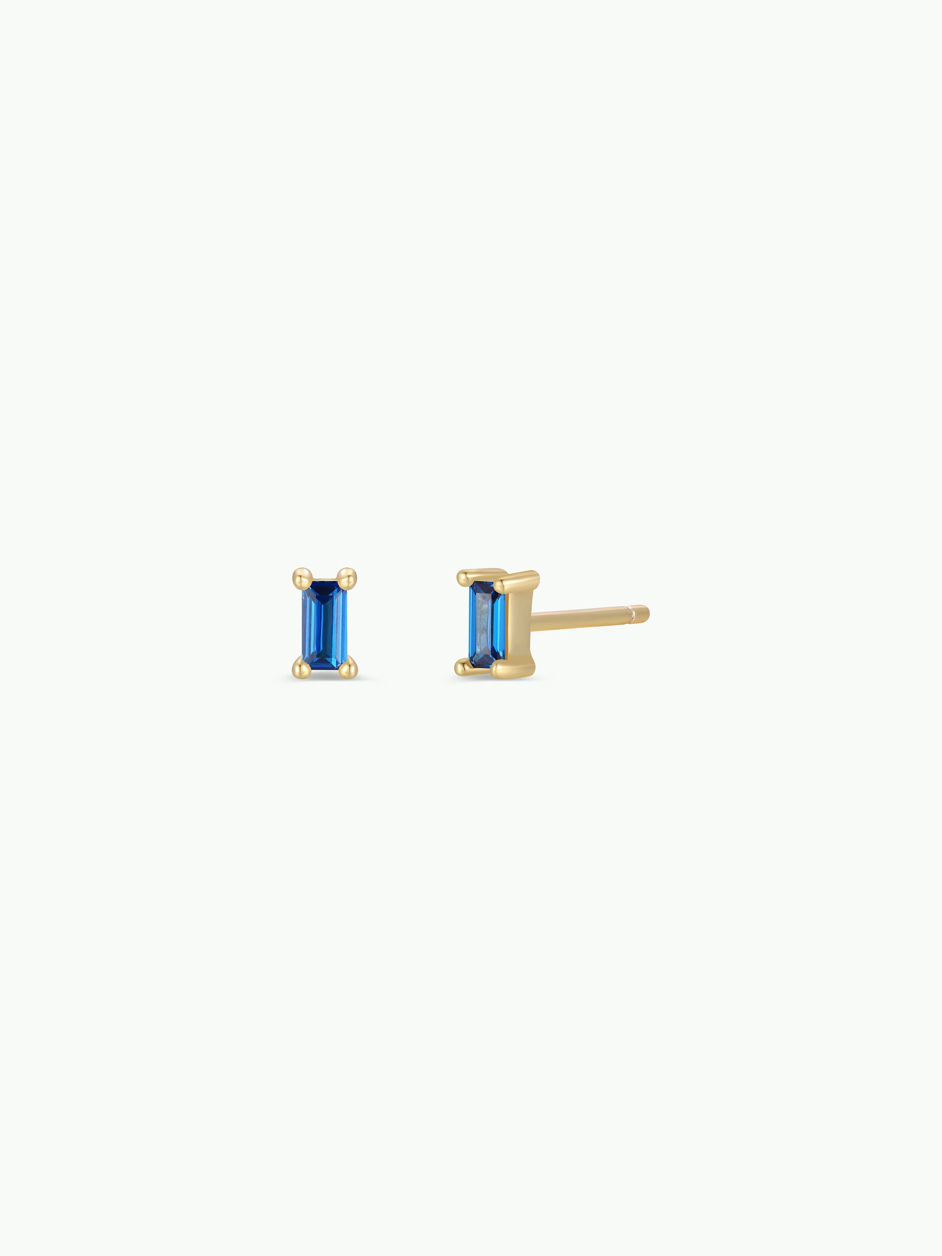Gold earrings with blue gemstones on a white background