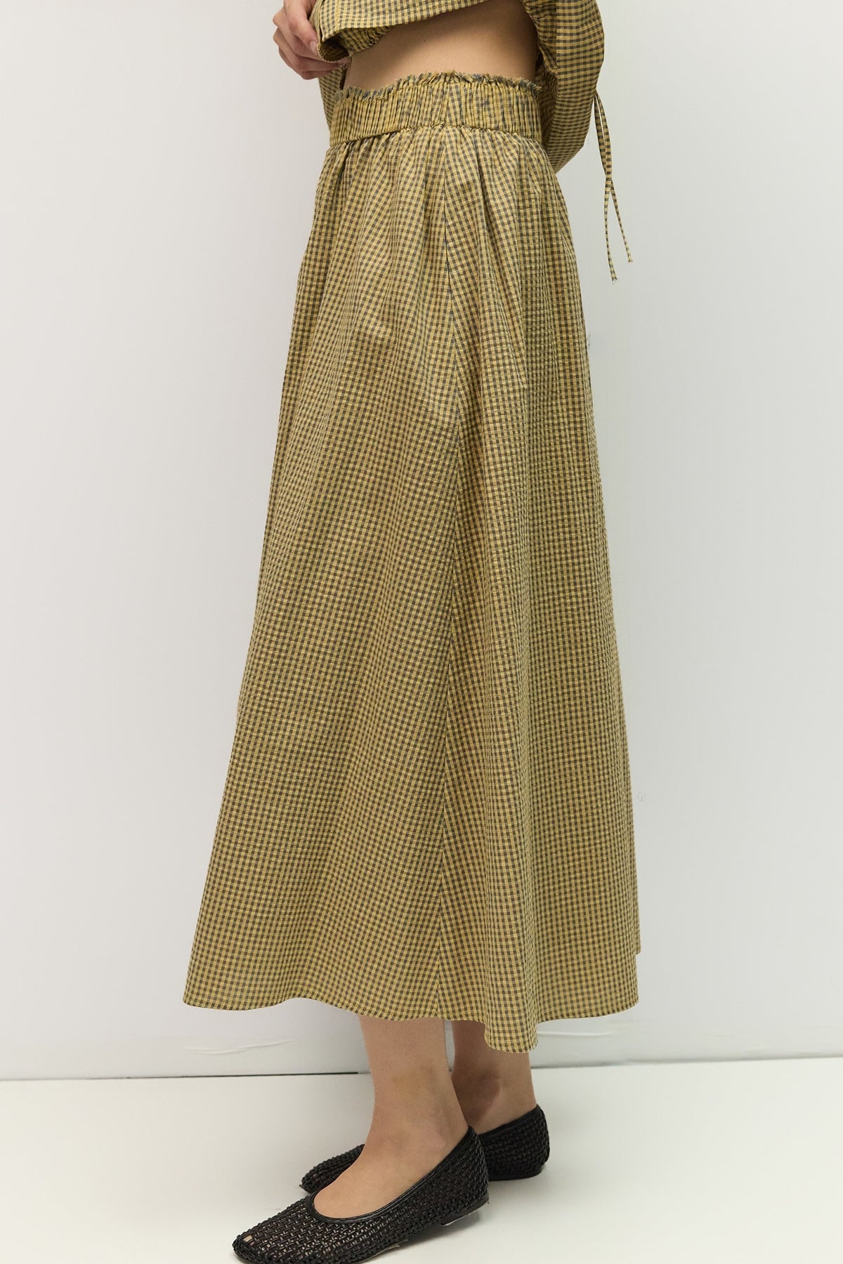 Person wearing a long green checkered skirt on a white background