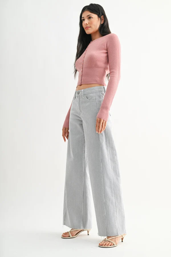 Woman wearing a pink cropped cardigan and light gray wide-leg jeans on a white background