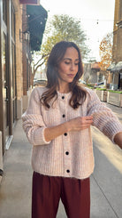 model wearing beautiful light rose colored cardigan and red pleated pants 