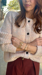 model wearing beautiful light rose colored cardigan and red pleated pants 