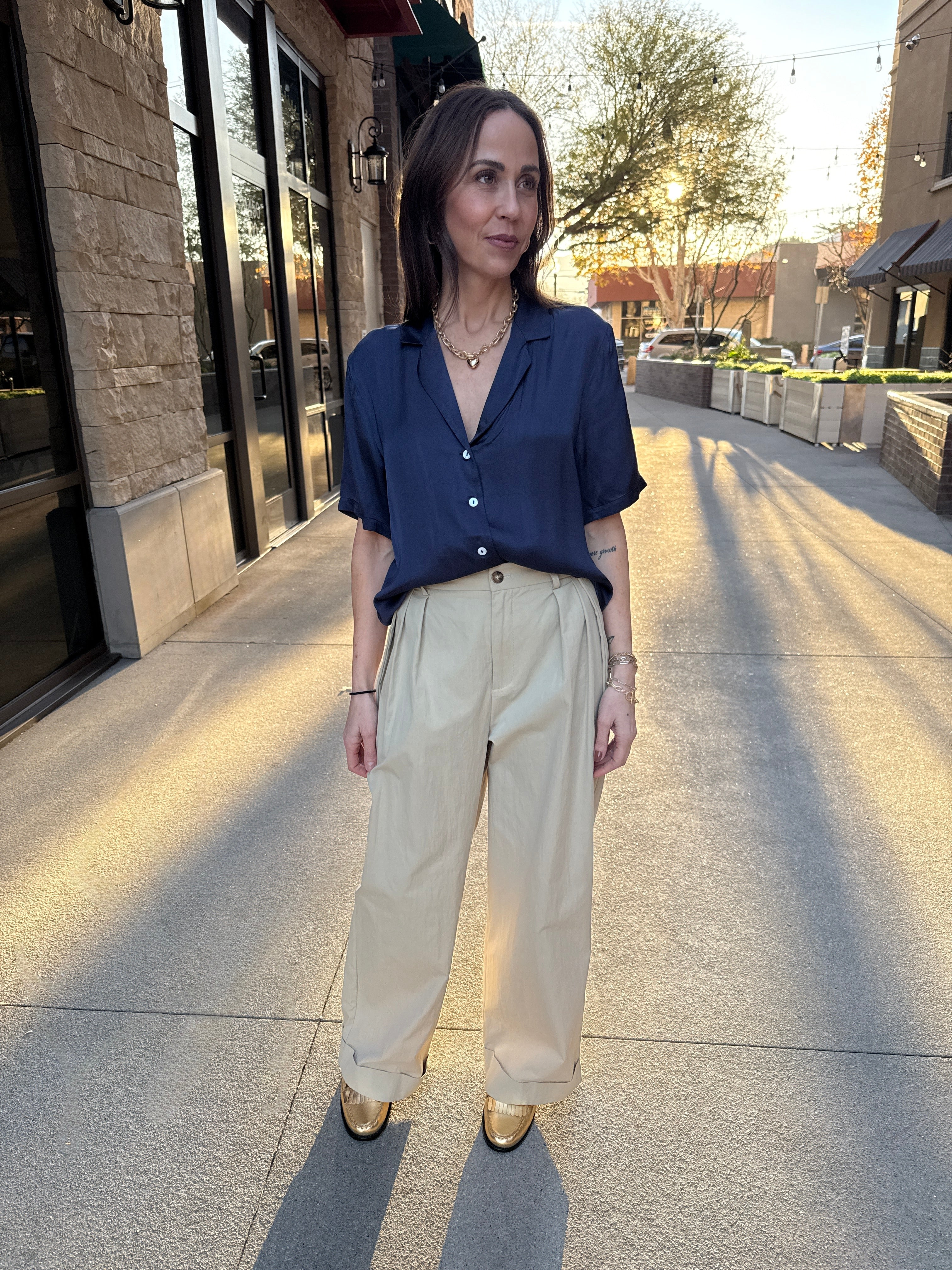 Model wearing silky, navy blue, white button up detail, blouse and khaki pants