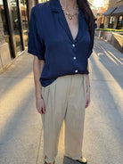 Model wearing silky, navy blue, white button up detail, blouse